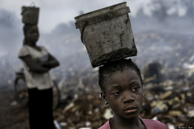 In an e-waste dump that kills nearly everything that it touches, Fati, 8, works with other children searching through hazardous waste in hopes to find whatever she can to exchange for pennies in order to survive. While balancing a bucket on her head with the little metal she has found, tears stream down her face as the result of the pain that comes with the Malaria she contracted some years ago. This is her life. ?Photo taken in Accra, Ghana on August 17, 2010.